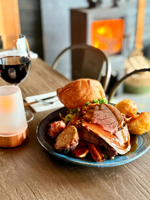 Sunday roast dinner with red wine by a fireplace