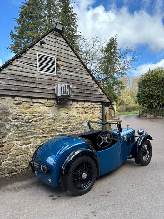 Blue vintage convertible parked outside a stone building