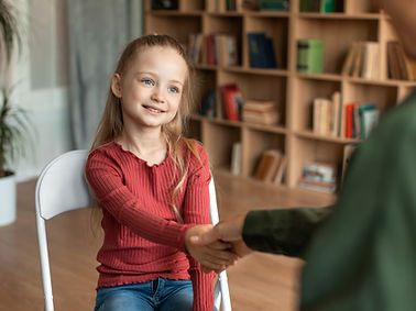 Pretty preschooler girl visiting psychotherapist, woman and child shaking hands, greeting