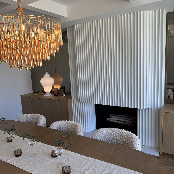 Modern dining room with gold chandelier and white fluted plaster fireplace