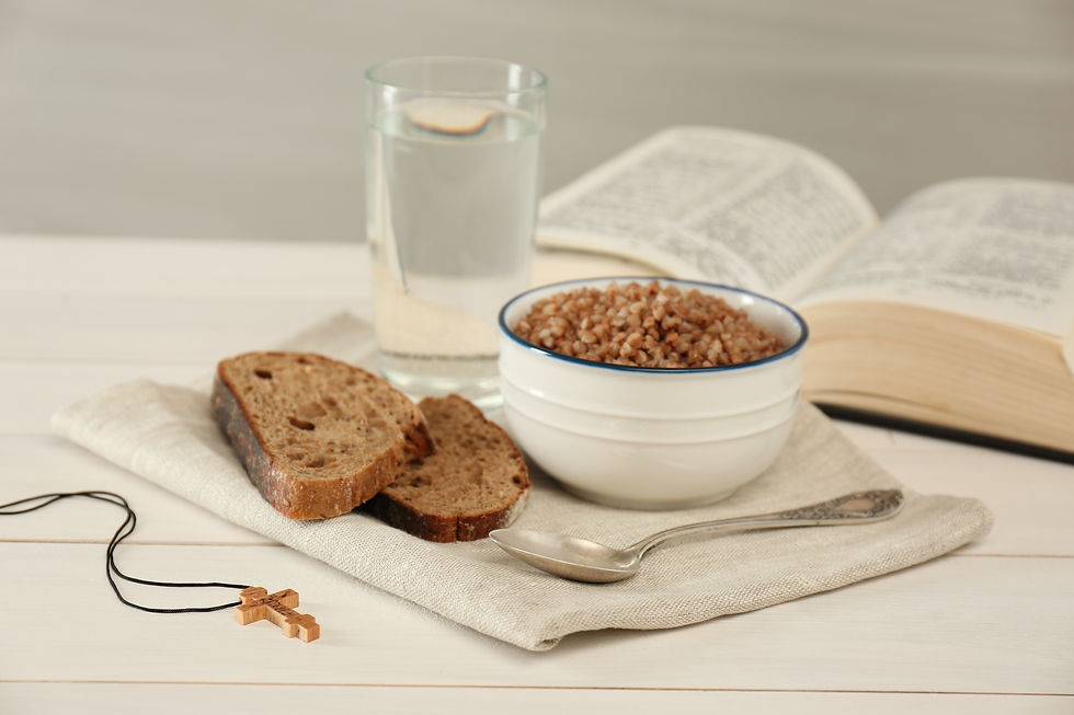 Open Bible next to a simple breakfast of cereal and bread and a glass of water. A cross on a necklace is laying to the side.
