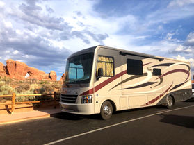 RV parked in front of red rock arches in Arches National Park. 