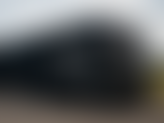 A luxury motorhome covered with a large black tarp with a youtube family's logo, WanderLuxe With Us, written in white on the side. 