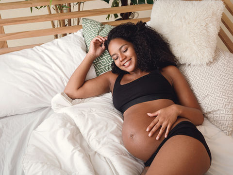 relaxed pregnant woman on bed looking lovingly at her belly