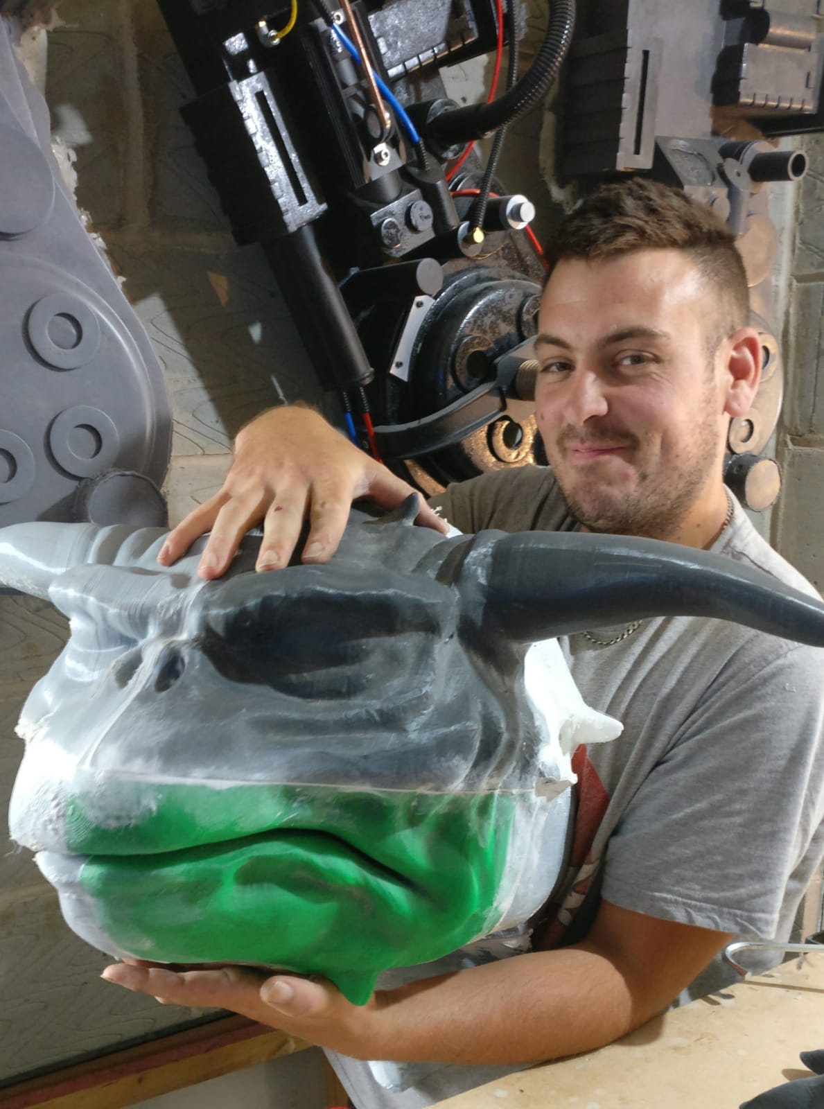 Man holding a painted mask with a smile in a workshop setting
