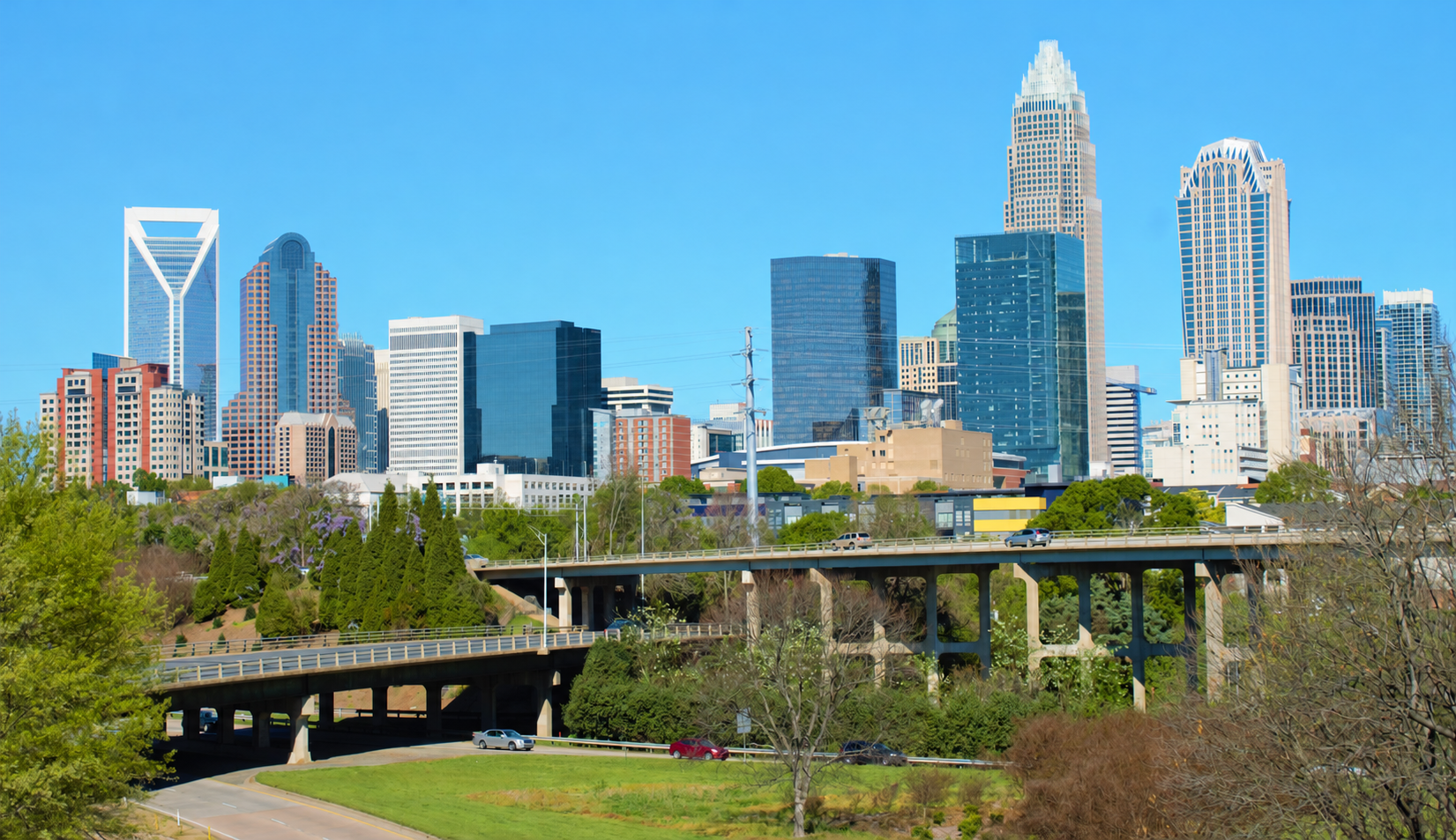 Charlotte skyline with roadway bridges and green foreground.