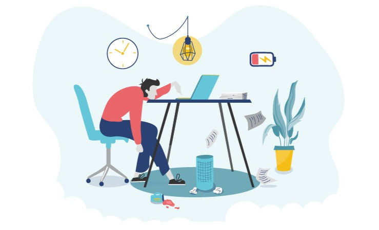 A man slumped over at his work desk with the low-battery symbol