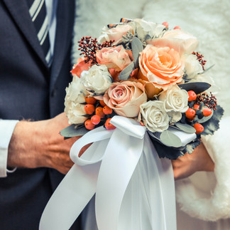 A stunning winter wedding bouquet featuring white roses, pinecones, and seasonal greenery.