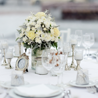 A stunning winter wedding tablescape featuring white and metallic decor, candlelit centerpieces, and seasonal greenery.