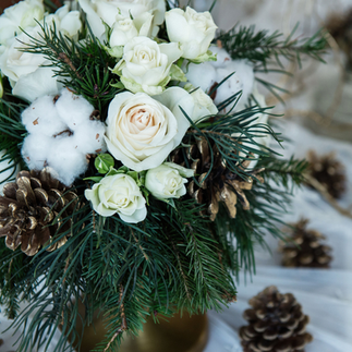 A stunning winter wedding bouquet featuring white roses, pinecones, and seasonal greenery.