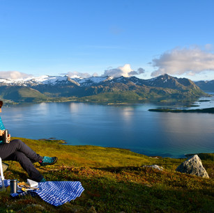 womam sitting having lunch in the mountain while looking at the ocean
