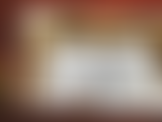 A framed photo sitting on a desk next to leaf. The photo is of two handwritten pages sitting on a table with a pen, surrounded by coffee and a journal.