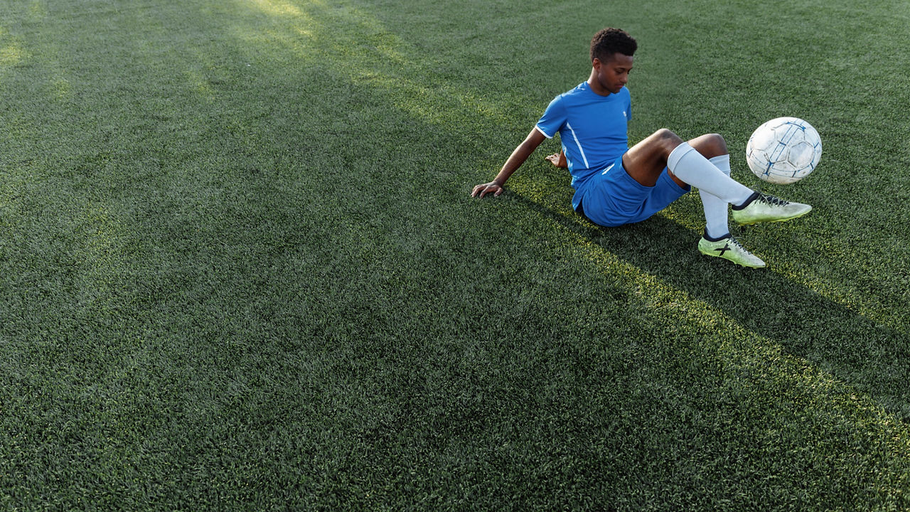 Sitzender Fußballspieler, der mit dem Ball jongliert