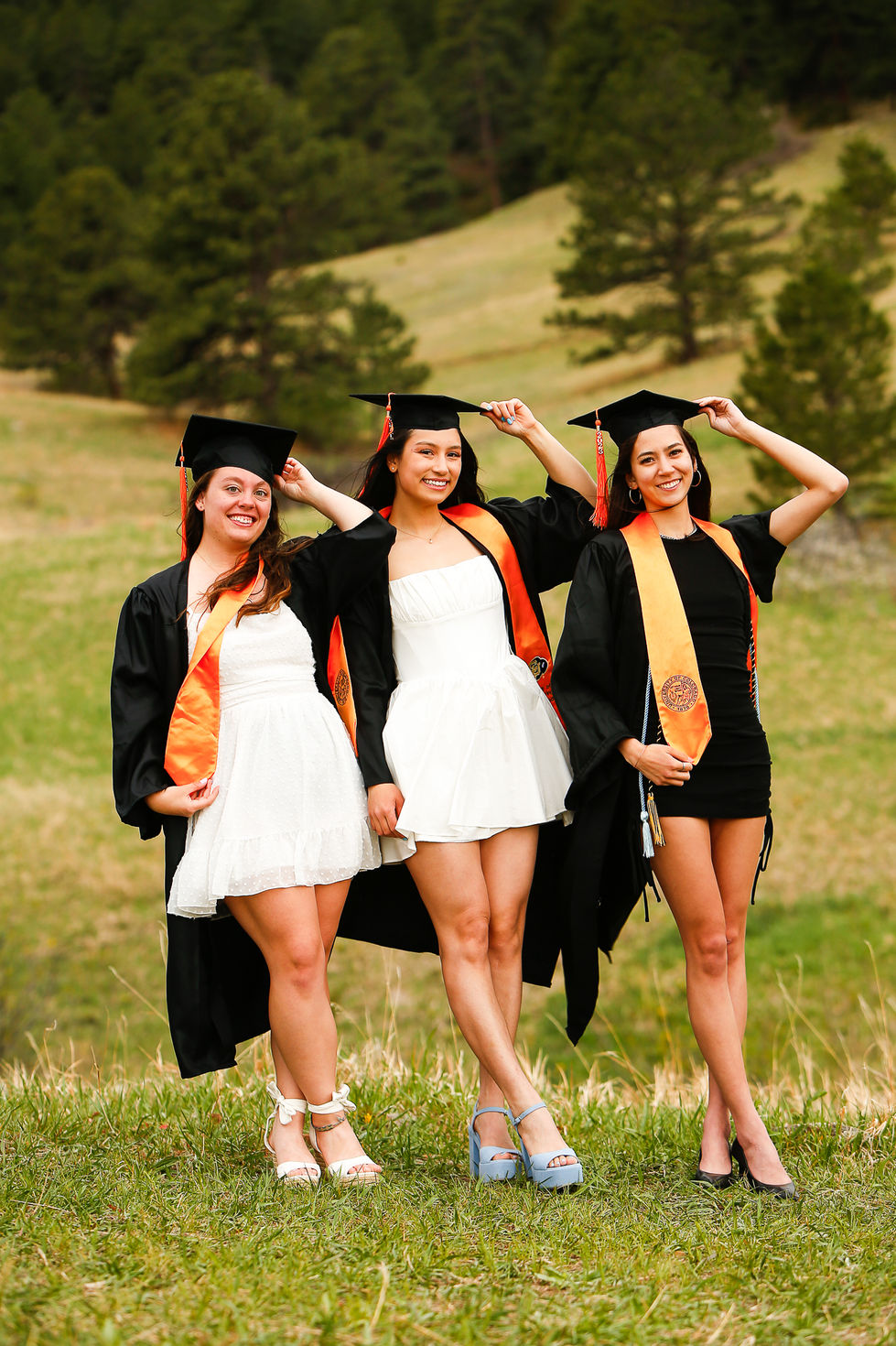 Three girls in cap and gowns at CU Boulder college graduation in Colorado