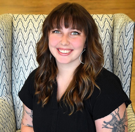 Smiling woman with floral arm tattoo sits in a patterned armchair. Collage Salon