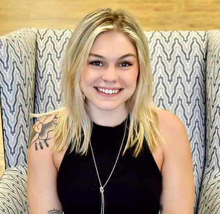 Smiling blonde woman wearing black dress seated in patterned chair Collage Salon