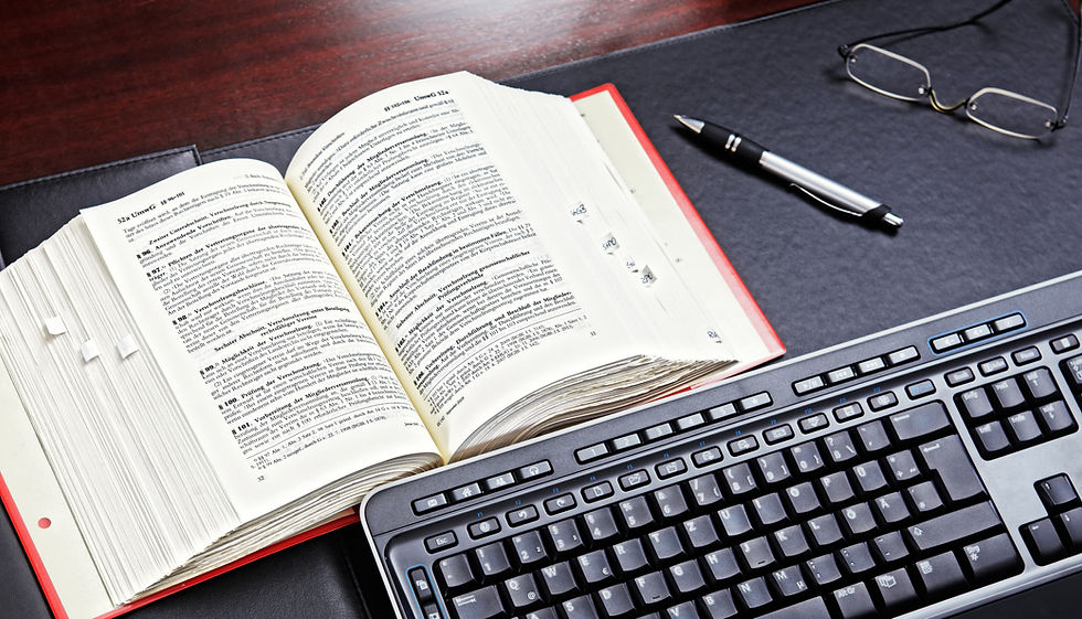 alt="Open glossary book titled ‘Business Valuation’ resting on a desk next to a keyboard"
