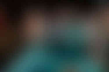 Indian bride and groom in matching emerald green outfits laughing and clapping during their Sangeet celebration at Garza Blanca Cancun.