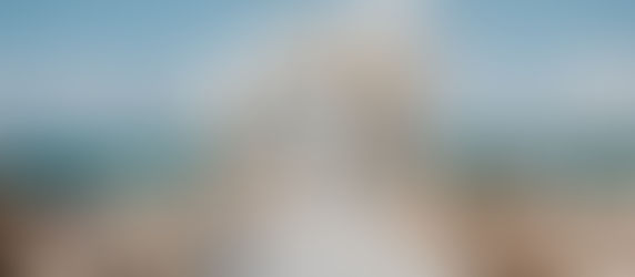 Gujarati bride and groom standing under a floral mandap on a beach in Mexico during their destination wedding ceremony, with turquoise ocean backdrop.