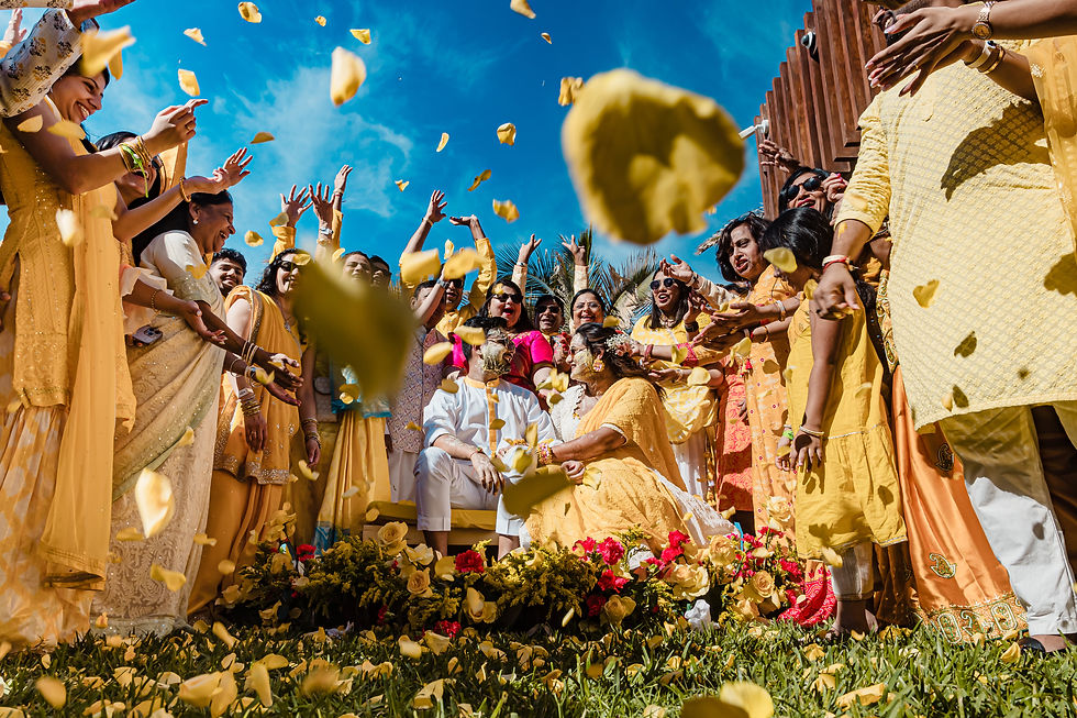 Joyful Haldi ceremony during an Indian destination wedding in Mexico with guests in yellow outfits throwing flower petals—pre-wedding ritual full of color and blessings