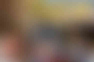 A mehndi artist applies intricate henna designs on a guest’s hand inside a Moon Palace Cancún suite, with tropical palm trees and sunlight reflecting through the window, blending tradition with the beauty of a destination wedding.