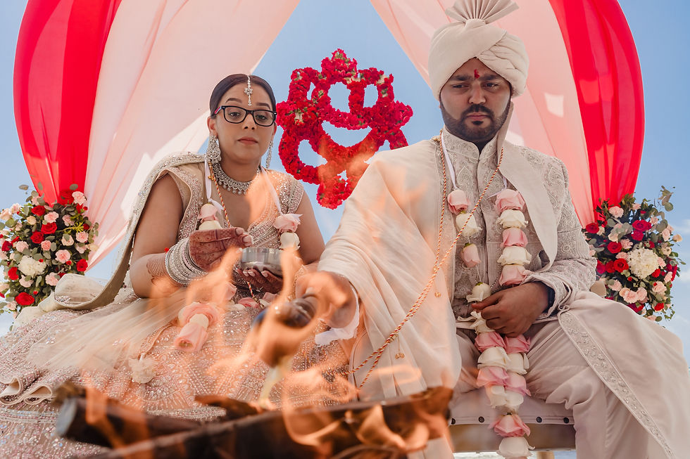 Bride and groom performing sacred fire rituals during their beach Hindu wedding at Grand Palladium Riviera Maya, with floral mandap decor.
