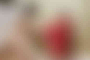 Indian bride in a red and gold saree laughs joyfully as a bridesmaid helps her put on shoes before the wedding ceremony at Garza Blanca Cancun.