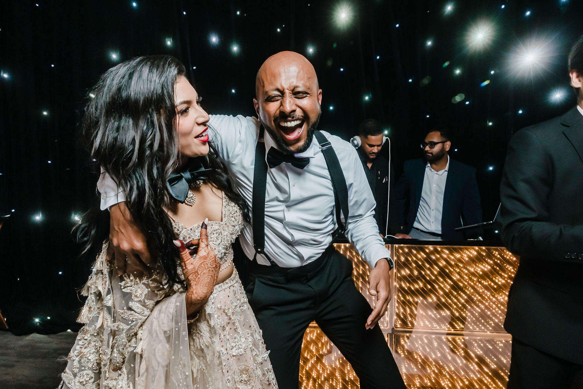 Groom surrounded by friends on the dance floor at Garza Blanca Cancun, singing and celebrating under twinkling fairy lights during the wedding reception.
