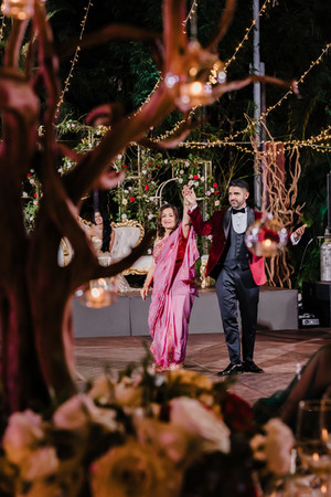 Groom and his mother share a joyful moment, holding hands and smiling as they walk the dance floor at Garza Blanca Puerto Vallarta, framed by candlelit floral centerpieces and twinkling string lights.
