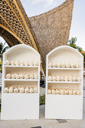 Fresh coconuts with custom monogram straws displayed on white shelves for Rhia and Bhavik’s Indian destination wedding at Garza Blanca Cancun.