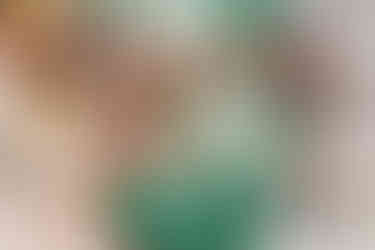 Close-up of bride Devina’s mehndi-adorned hands holding betel leaves and rice during a sacred Hindu wedding ritual, assisted by women in traditional green silk sarees at Moon Palace Cancún.