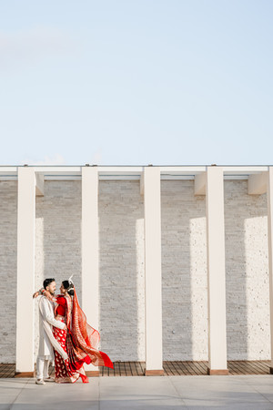 Indian bride and groom share a joyful embrace, her red saree flowing in the breeze at Garza Blanca Cancun