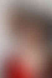 Close-up portrait of an Indian groom in an ivory sherwani gazing at the camera while the bride in a red saree and elaborate jewelry stands in soft focus in the foreground during their Garza Blanca Cancun wedding.