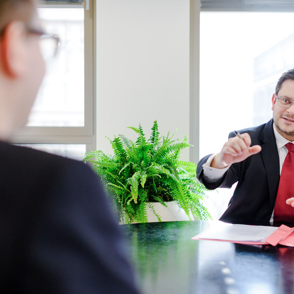 Businessfotografie eines Anwalts, der seinem Mandanten einen Sachverhalt erklärt.