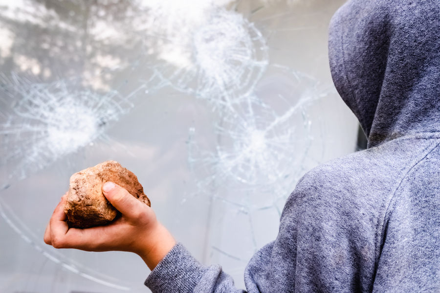 Burglar with rock trying to break into window with 3M Safety and Security Window Film installed.