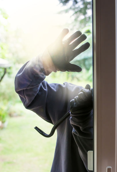 Burglar with crowbar trying to break into window