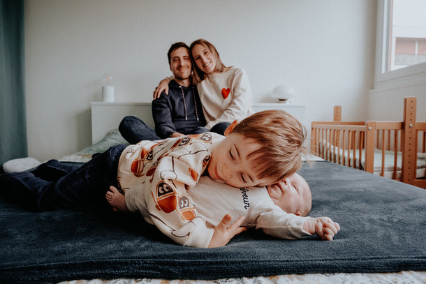 Séance photo naissance à Paris. Câlin fratrie pendant shooting nouveau-né à domicile.