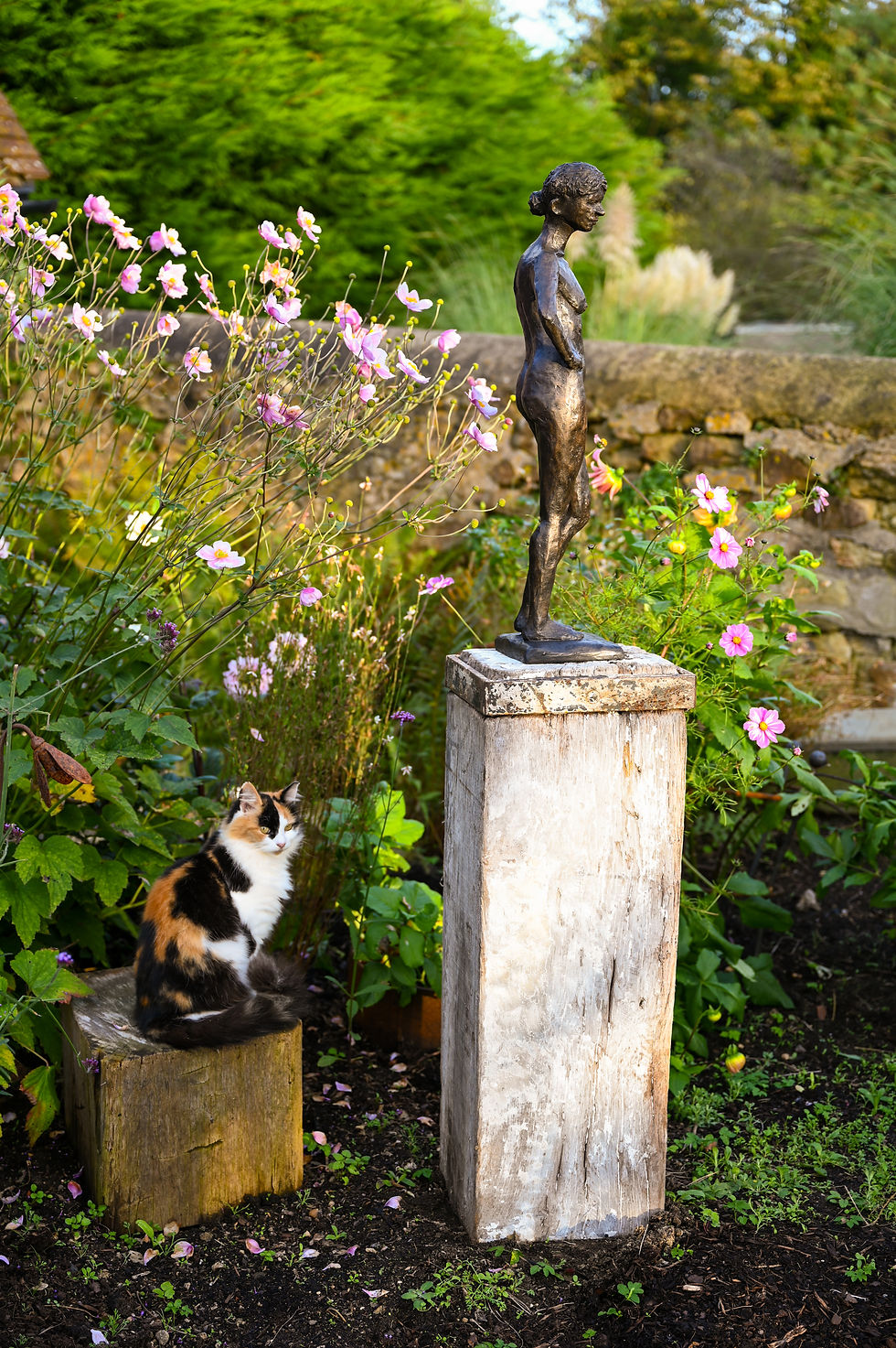 Thumbnail: Bronze female figure with hand on hip standing among spring flowers in a garden.