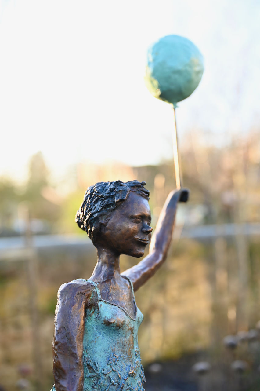 close up of torso of young girl wearing turquoise dress holding a balloon.