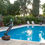 Thumbnail: Bronze figure in a dive pose beside a sunlit pool, reflecting surrounding garden trees and evening sky.