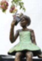 Girl in green dress holding a book close to her face, with a rabbit figure popping out as she reads.