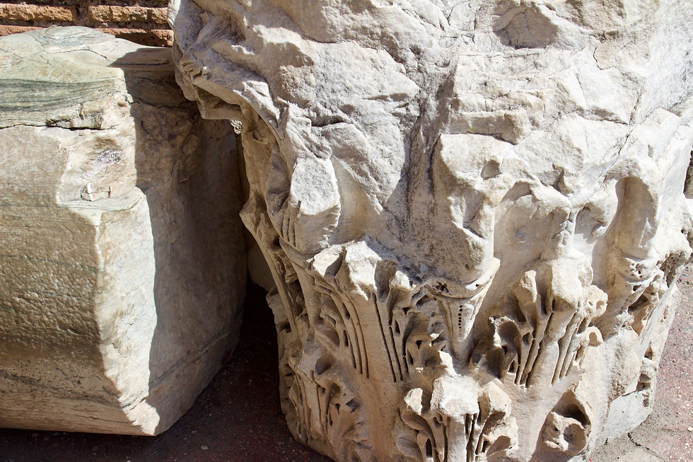 Intricate frieze carvings on the upper white stone pillars that remain in the Roman Colosseum.