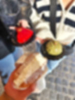 Three women hold out pastries in front of them, one shaped like a red heart, one a pistachio mound, and the other a delicious maritozzo.