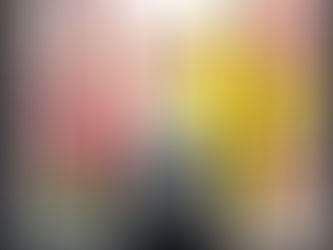 A suitcase stands by a large window with blossoming pink and yellow flowers outside. Bright, serene travel scene.