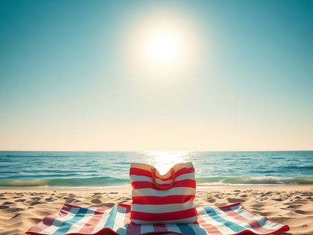 Striped beach bag on a striped towel, set on sandy beach. Sun shines brightly over calm ocean, creating a relaxing and warm mood.
