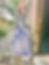 Tile art of a woman in blue dress stands by a building. Cobblestone path, plants, and green bench in view. Sign reads: "Mind the door stopper."