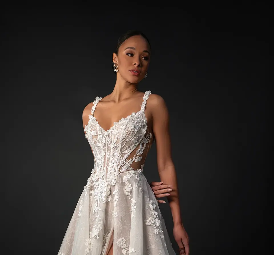 Romantic Floral V-Neckline A-Line Wedding Dress with Spaghetti Straps
Delicately crafted yet bold in design, Style 1899 combines classic bridal elegance with modern, sexy details in this romantic floral wedding dress. The princess-cut gown features graceful 3D floral spaghetti straps that meet a flattering V-neckline. A sheer bodice highlights the figure with hand-placed floral embellishments and side cutouts, flowing into an illusion open back with shimmering buttons. From a sleek basque waist, the flowing A-line skirt (available in lined or unlined options) continues the floral theme with romantic lace beneath scattered 3D flowers and a high leg slit for an alluring touch. Free-spirited and fashion-forward, this boho floral wedding dress was made for the modern bride.