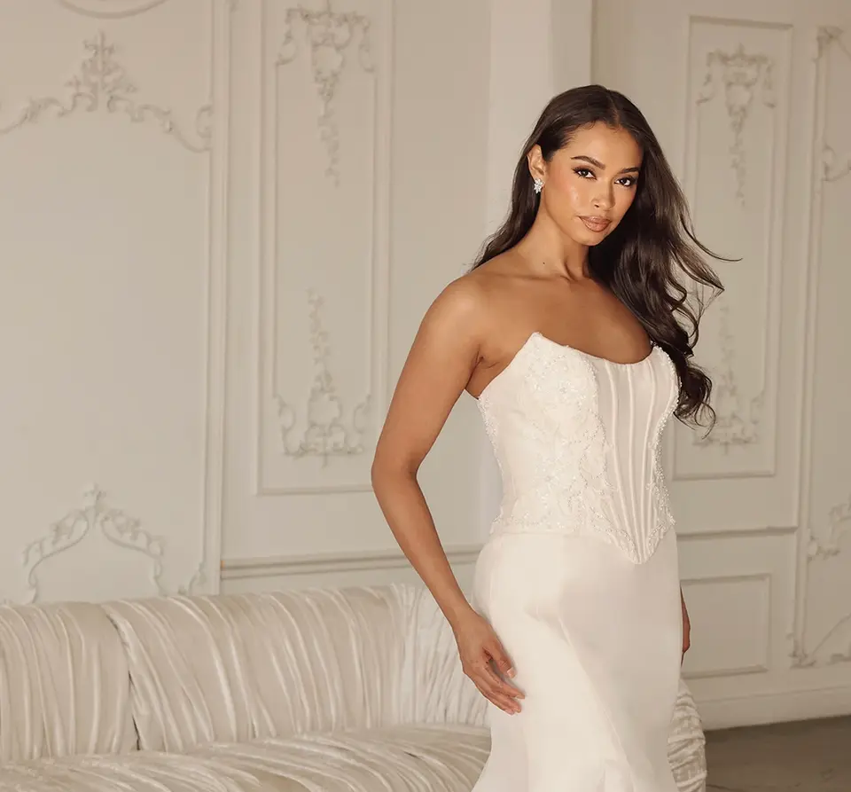 Modern Strapless Corset Fit-and-Flare Wedding Dress in Silk
For the fashion-forward bride with timeless style, this romantic corset wedding dress in luxe silk presents a unique no-lace, two-piece bridal look. From a strapless scoop neckline, Style 1902 features an embellished silk corset bodice adorned with scrolling beaded details that elegantly frame the figure and accentuate the Basque waist. A traditional tied corset closure in the back meets a skirt-length row of fabric-covered buttons as the fit-and-flare silhouette dramatically flares past the knee to form a lace-embellished sweeping train. A modern silk wedding dress, this designer bridal gown offers luxury and contemporary elegance for the classic bride.