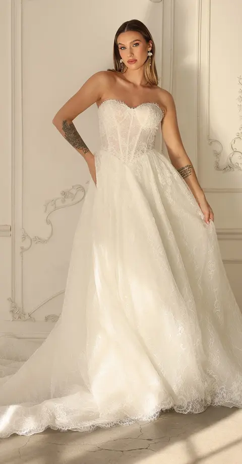 Strapless Romantic Lace Corset A-Line Wedding Dress with Sweetheart Neckline
Style 1882 epitomizes romantic elegance, offering a timeless A-line silhouette in elegant allover floral lace. This sweetheart neckline wedding dress is enhanced by exposed corset boning, giving the bodice a fitted and structured look thatās available with a lined or unlined option for the brideās desired level of sheerness. In the back, a gown-length row of fabric-covered buttons brings an element of timelessness as a regal basque waist emphasizes the natural figure and A-line silhouette. Finally, a scalloped lace hem adds a delicate, romantic touch as this modern corset wedding dress floats gracefully down the aisle.