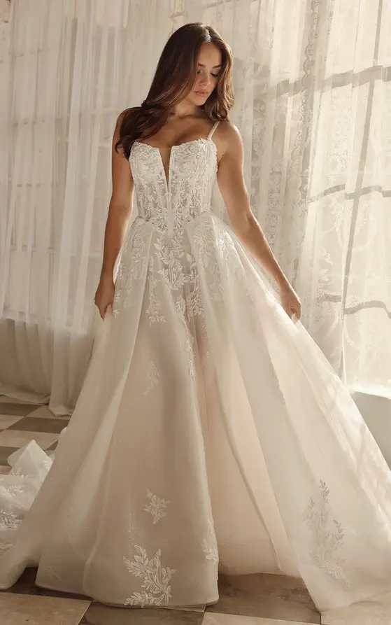 Martina Liana style ML1833
For the bride who dreams of a modern day fairytale, this style combines princess-inspired romance with a sexy, sophisticated edge. This romantic lace bridal gown features shimmering beaded spaghetti straps that connect to a sheer corset-style bodice and plunging notch neckline. Glittering beaded accents dance across leafy floral appliquƩ lace, cascading over the basque waistline and seamlessly transitioning into the full A-line skirt of glittering tulle, with pockets and a sexy leg slit for a modern touch. Available in both lined and unlined options for a customizable level of sheerness, the skirt flows into a delicate floating hemline complete with scattered floral lace appliquƩs to complete this romantic bridal gown.